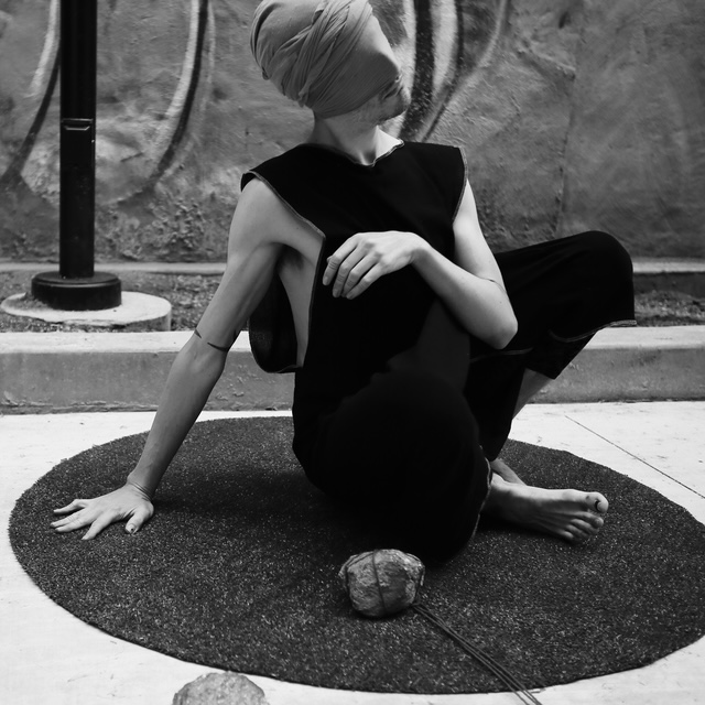 Male sitting crosslegged on floor, with fabric covering face