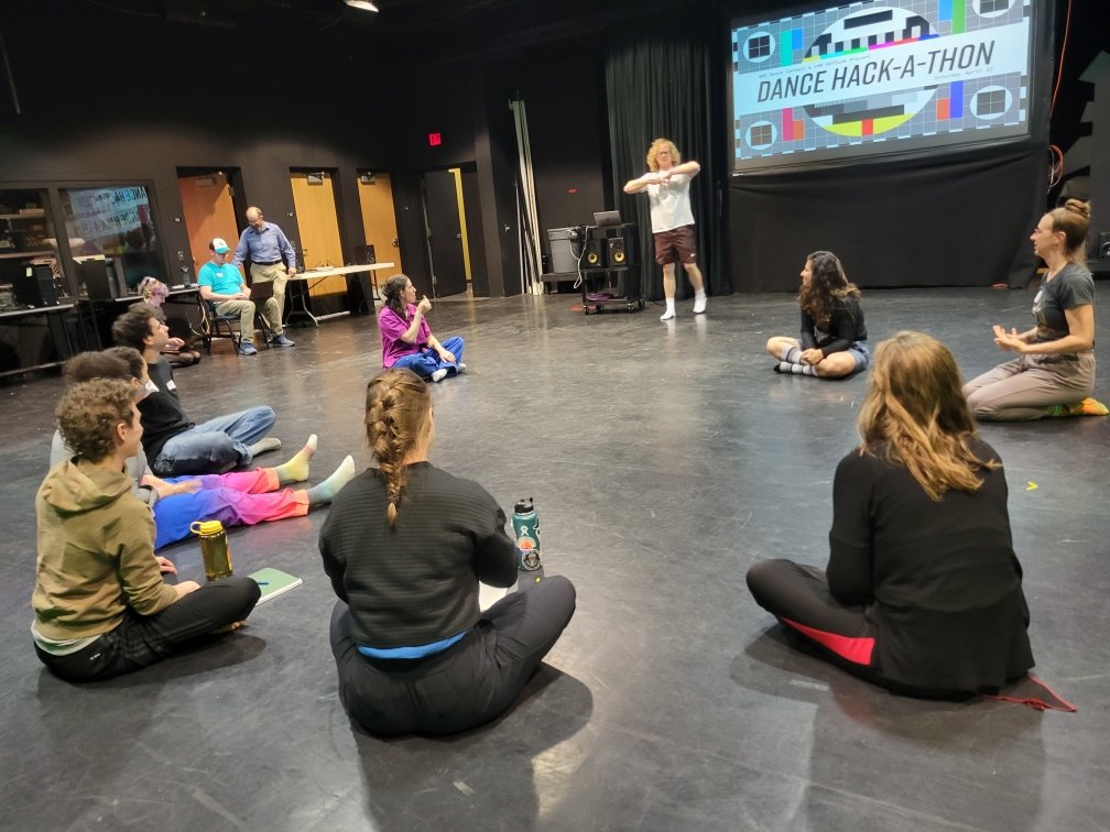 Group sitting on floor, listening to speaker